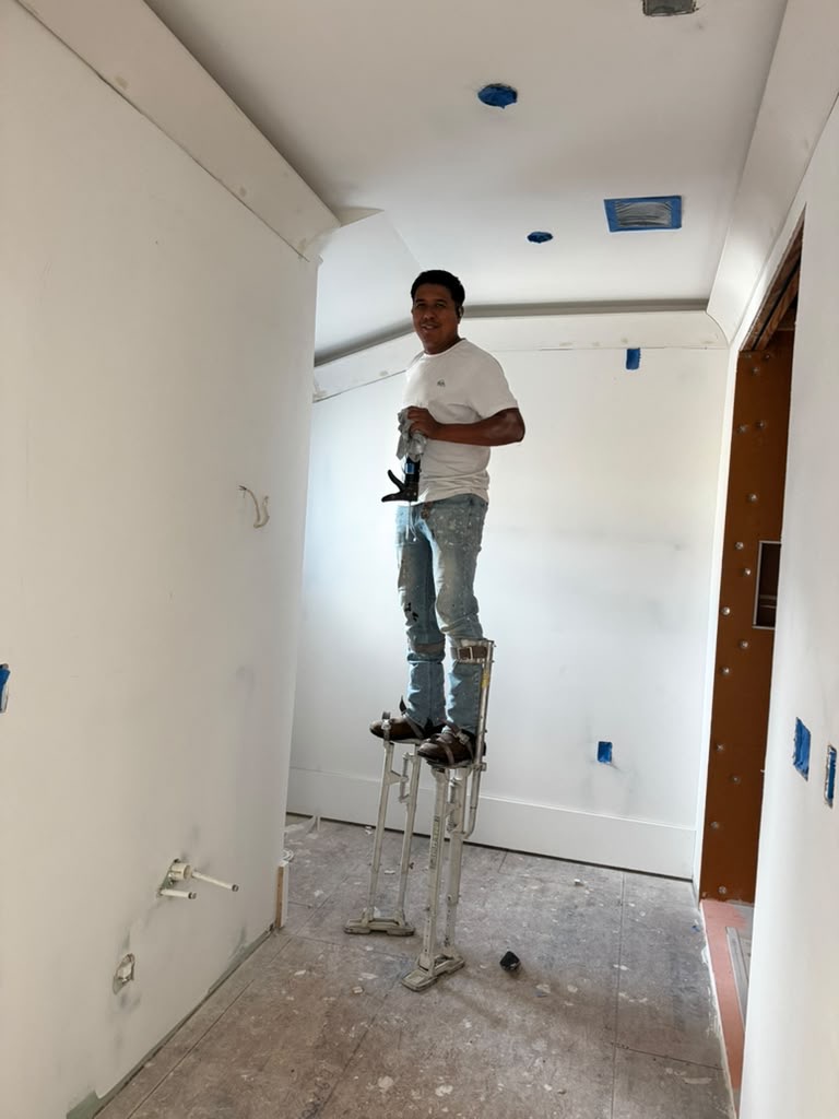 Finishing drywall on stilts in a finished room.