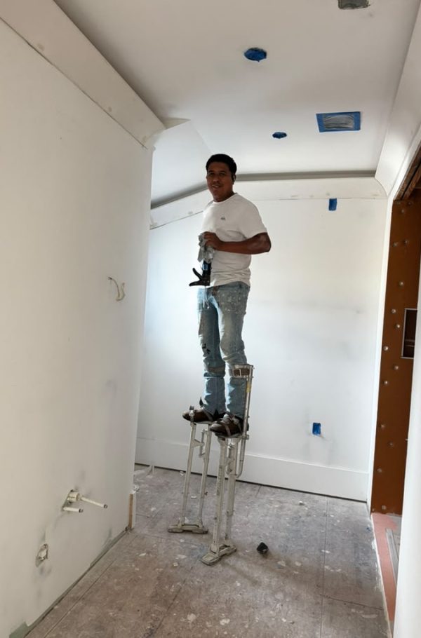 Finishing drywall on stilts in a finished room.
